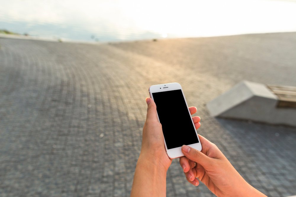 une personne utlise un smartphone près d'une plage