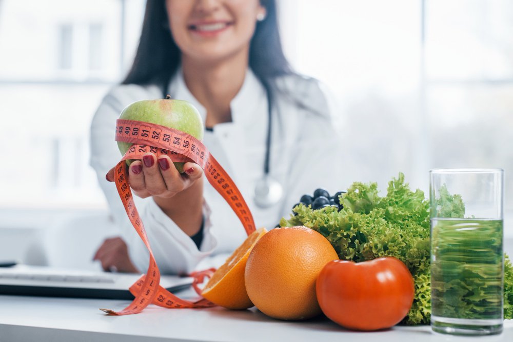 une médecin tenant une pomme et un mètre avec des aliments sains