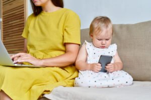un bébé joue avec un téléphone près de sa mère