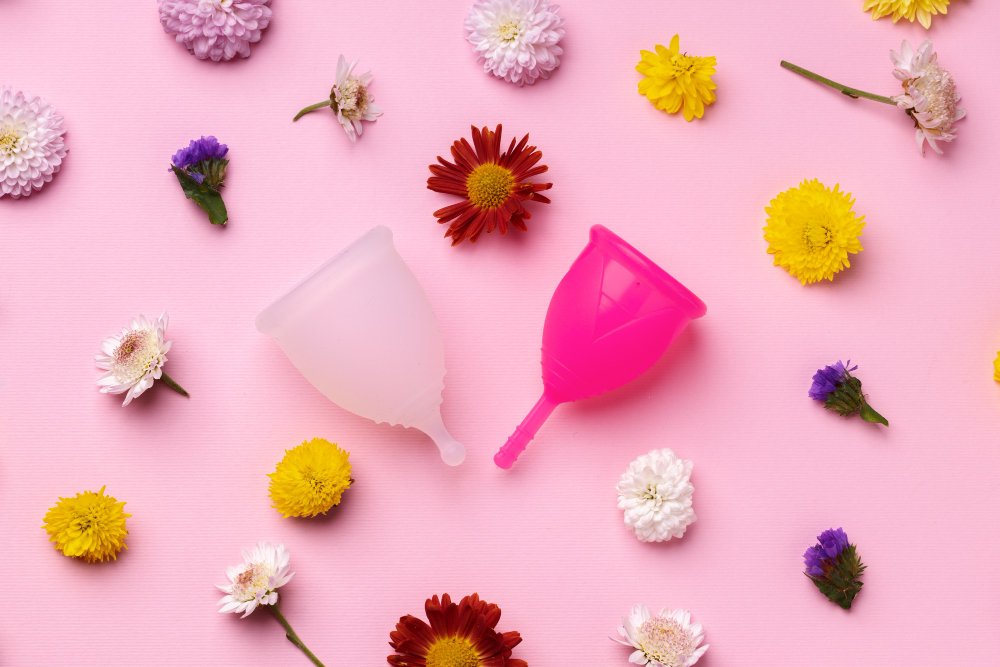 deux cup menstruelle entouré de fleurs