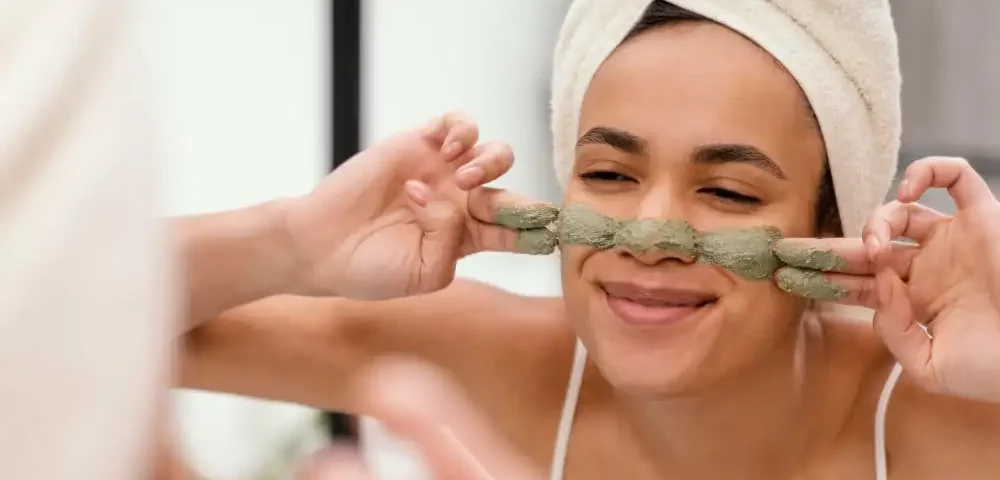 Une femme qui se fait un masque d'argile vert